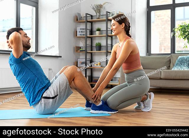 man with personal trainer doing sit ups at home