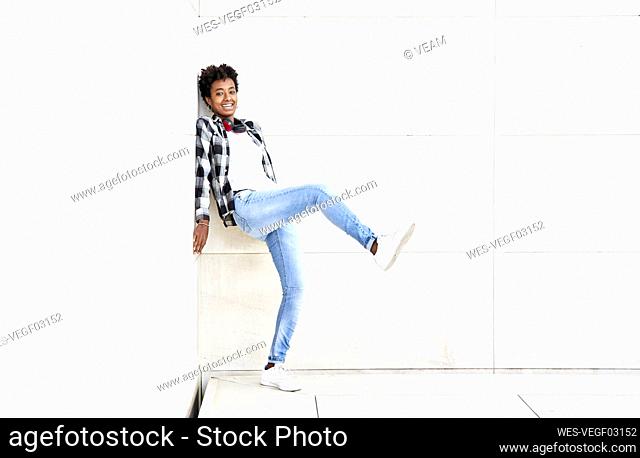 Playful young female hipster standing against white wall