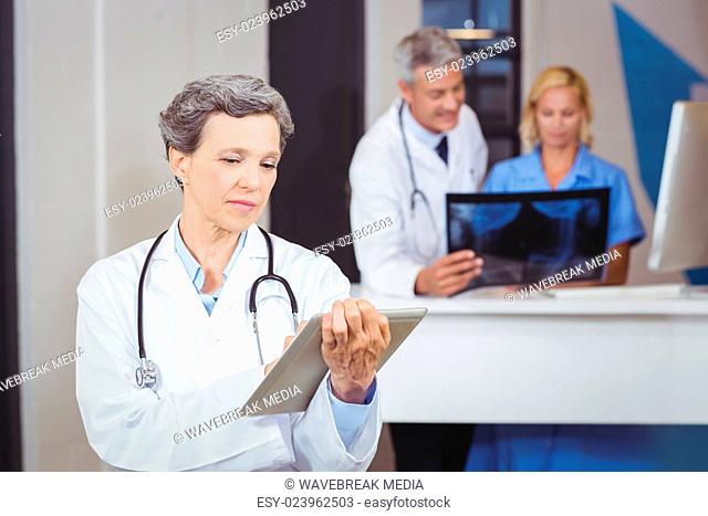 Female doctor using digital tablet with colleague checking X-ray