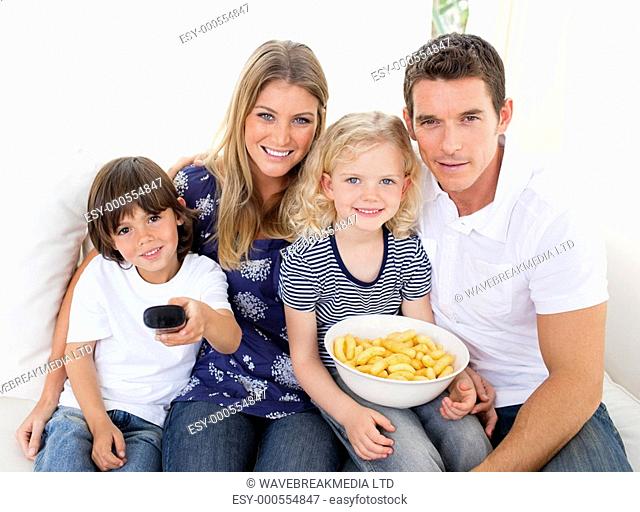 Loving family watching television sitting on sofa at home
