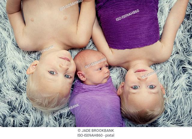 Siblings lying on carpet