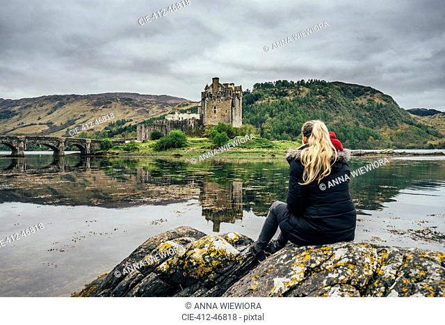 Woman enjoying view of remote, waterfront castle, Scotland