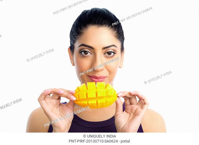 Portrait of a woman holding a slice of mango