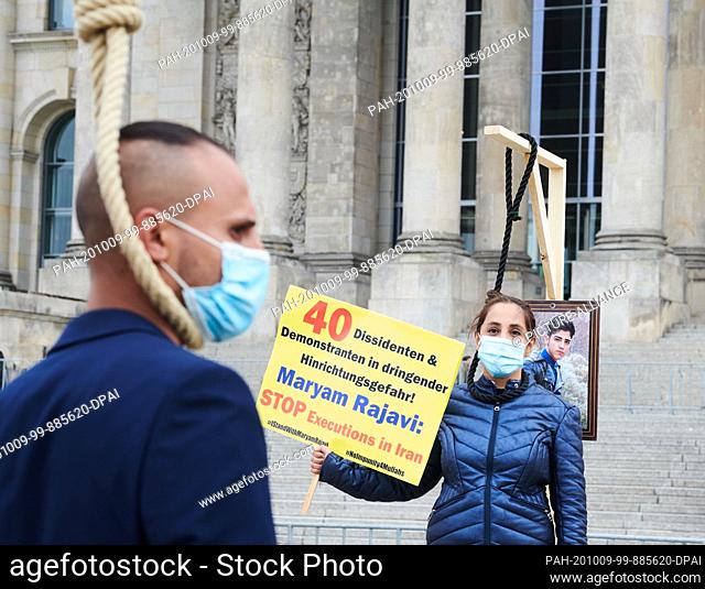 08 October 2020, Berlin: Two demonstrators hang symbolically from a gallows in front of the Reichstag. The Iranian exile community is demonstrating in front of...