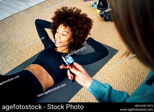 Smiling young woman with hands behind head working out at home