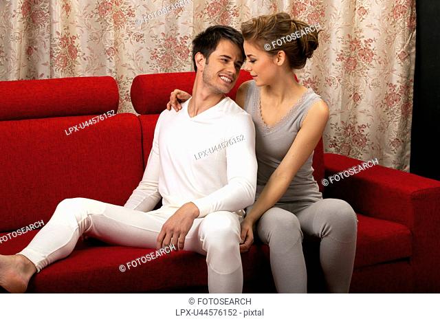 Couple in long underwear sitting on sofa