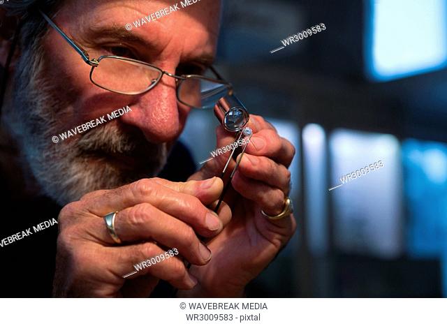 Goldsmith using magnifying glass in workshop