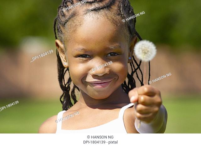 Girl holding a dandelion and smiling