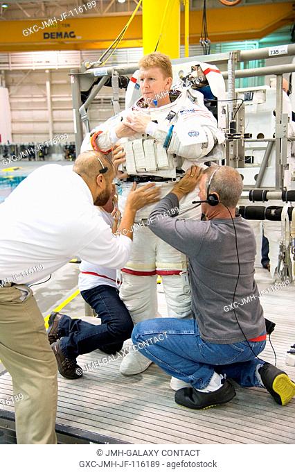 European Space Agency astronaut Timothy Peake gets help donning a training version of his Extravehicular Mobility Unit (EMU) spacesuit in preparation for a...