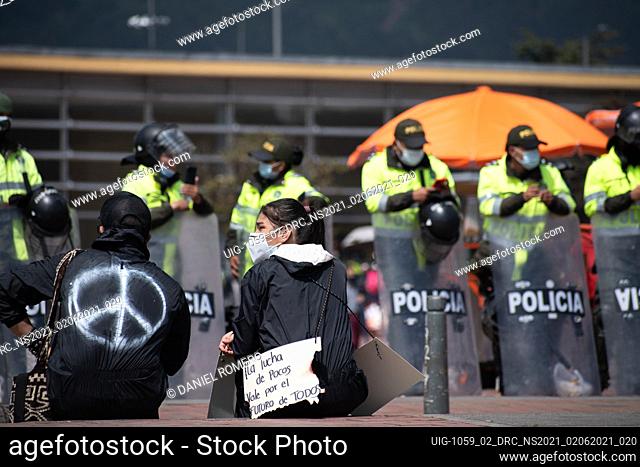 With the police behind her, a protester holds up a sign that reads ""Everyone's Fight for Everyone's Values."" on a new day of anti-government protest in Bogotá