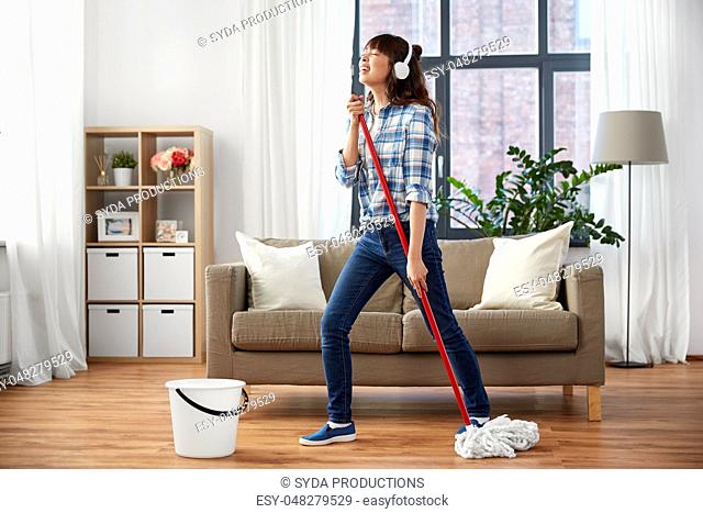 happy asian woman with mop cleaning floor at home