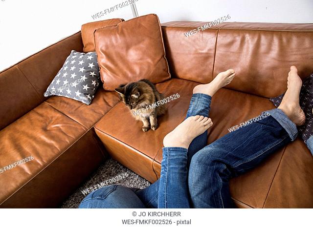 Couple lying on floor, legs on couch, cat watching