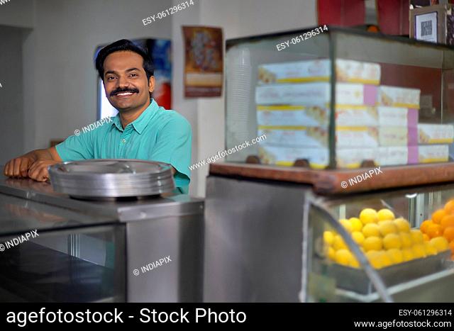 Portrait of happy Sweet shop owner standing at counter