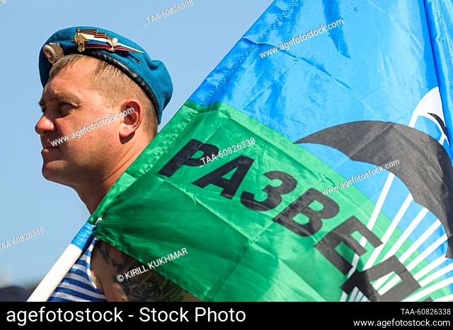 RUSSIA, NOVOSIBIRSK REGION - AUGUST 2, 2023: A former Airborne Forces serviceman in a telnyashka holding a flag is seen during celebrations in the town of...