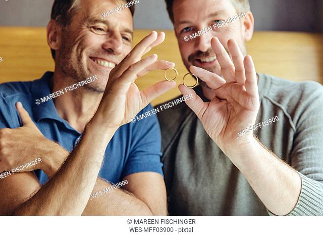 Happy gay couple holding up their wedding rings