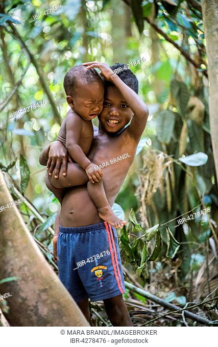 Young boy, aboriginal Orang Asil, holding his crying baby brother in his arms, indigenous culture, tropical rainforest, Taman Negara, Malaysia