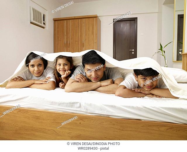 Parents with children under bed sheet lying on bed in bedroom MR702R, MR702S, MR702T, MR702U