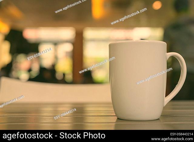 Coffee cup on wooden table in restaurant with defocused background and bokeh effect