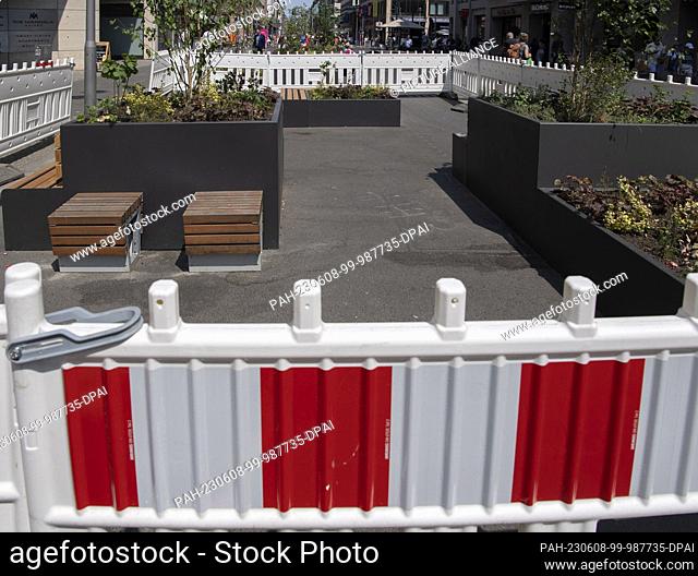 08 June 2023, Berlin: Barrier barks stand around giant flower tubs and seating on Friedrichstraße as a cyclist passes by
