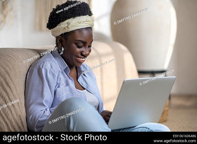 Online chat. African american woman sitting on the sofa and spending time in chat online