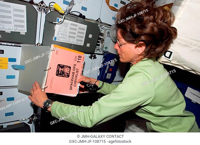 Astronaut Barbara R. Morgan, STS-118 mission specialist, refers to a procedures checklist on the middeck of Space Shuttle Endeavour while docked with the...