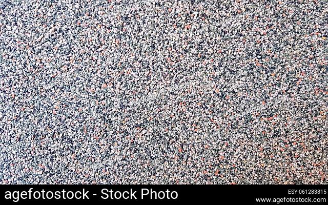 Gray concrete surface with multi-colored marble chips. Foreground. Dark gray marble chips. Wall, facade trimmed with marble chips