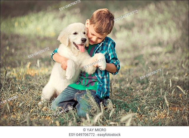 Cute handsome boy teen with blue eyes playing outdoor amazing white pink labrador retriever puppy enjoying summer sunny day vacation weekend with full happyness