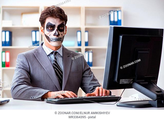 Businessman with scary face mask working in office