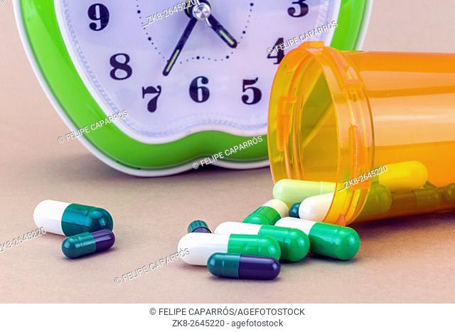 Pills spilling from an open bottle isolated on brown background
