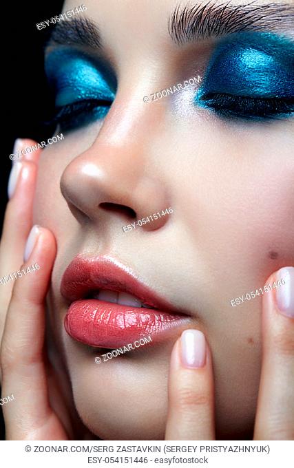 Closeup macro portrait of female with hand near face . Woman with evening beauty makeup. Girl with perfect skin and blue-green smoky eyes eye shadows