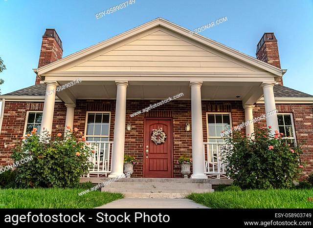 Front facade of a modern house with pillars. Front facade of a modern house with pillars or columns flanking the porch. A front door in a low angle view with...