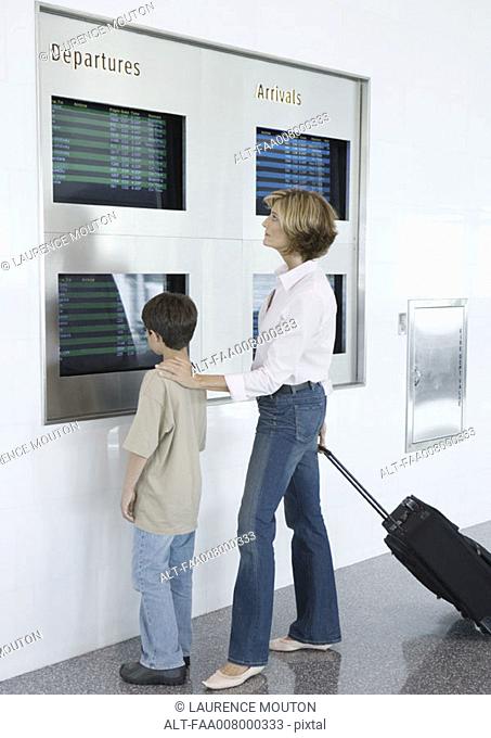 Woman and boy looking at departure board in airport