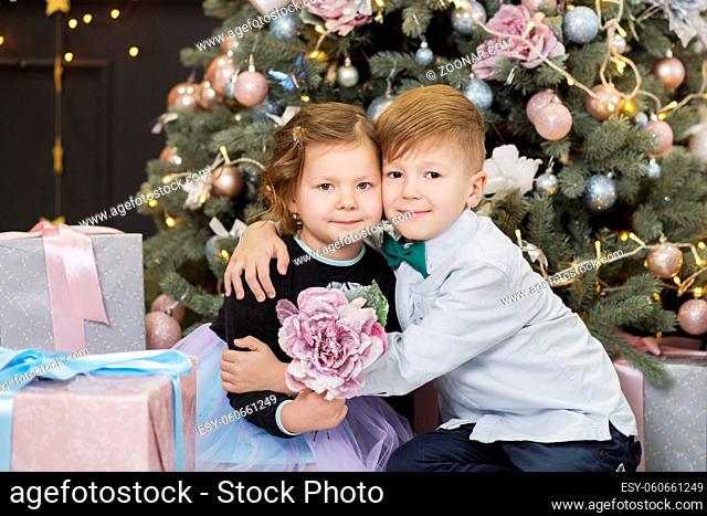 Portrait of a happy children - boy and girl. Little kids in Christmas decorations. Brother and sister hugging