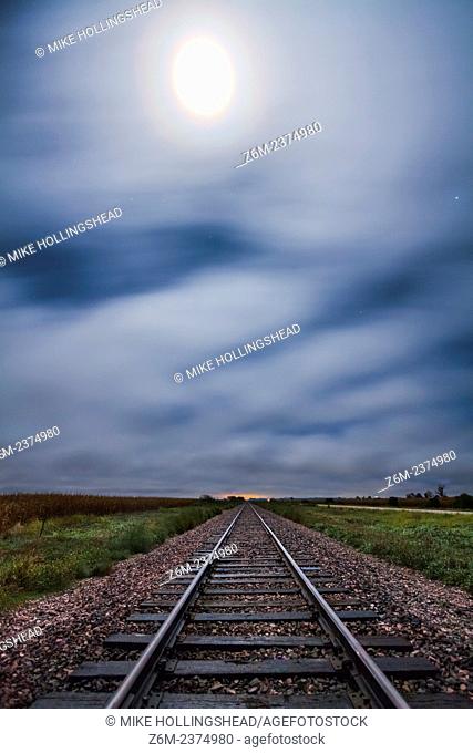 Fog blows west off the hills in western Iowa above train tracks lit by the moon which also had a vivid corona