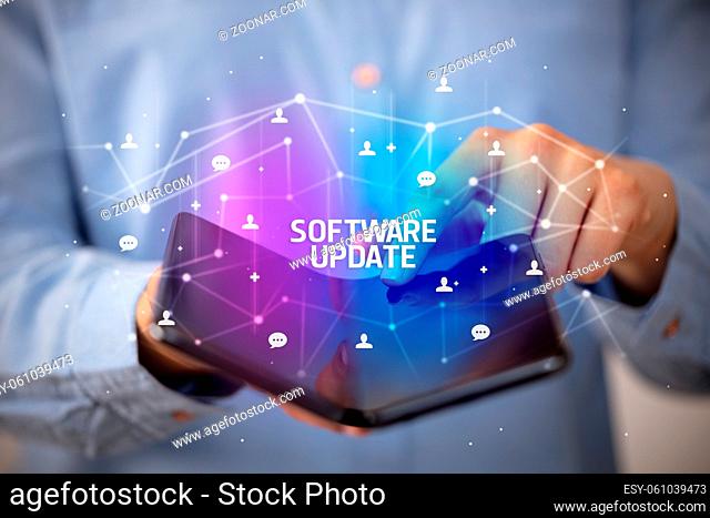 Businessman holding a foldable smartphone with SOFTWARE UPDATE inscription, new technology concept