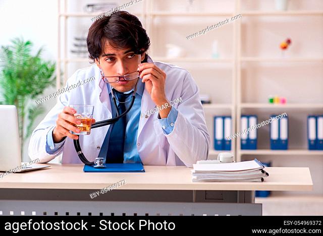Young male doctor drinking in the office