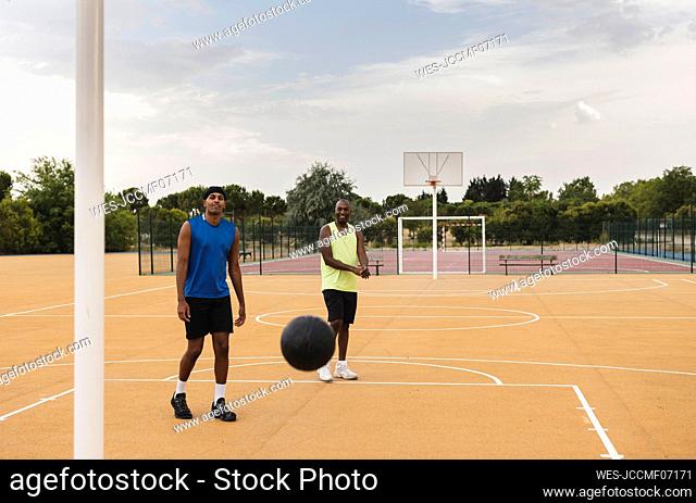 Father and son looking at falling basketball in sports court