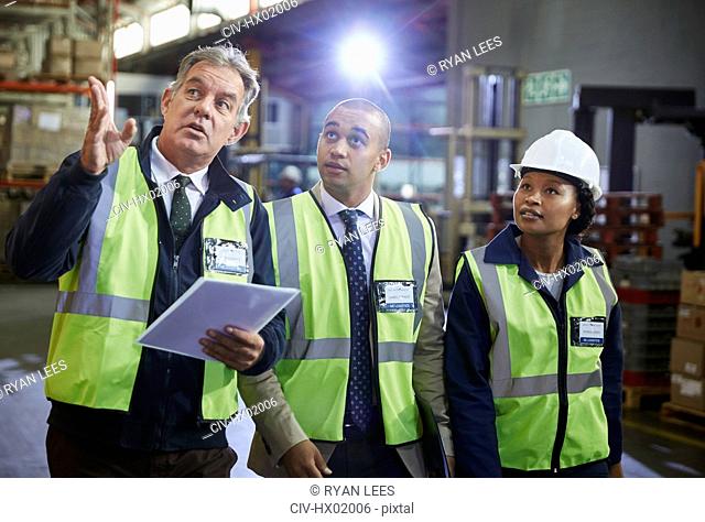 Managers and worker talking looking up in distribution warehouse