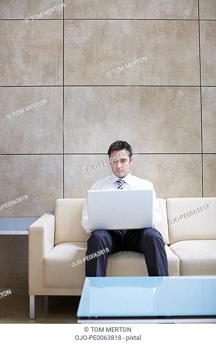 Businessman using laptop in hotel lobby