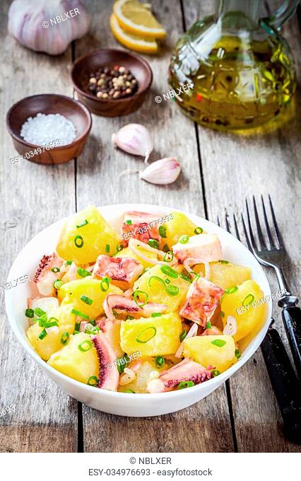 Italian food: salad with octopus, potatoes and onions on rustic background