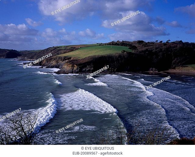 Sea and coastline west of Dodman Point. Sheltered, sandy cove with trees and fields sloping away to cliffs