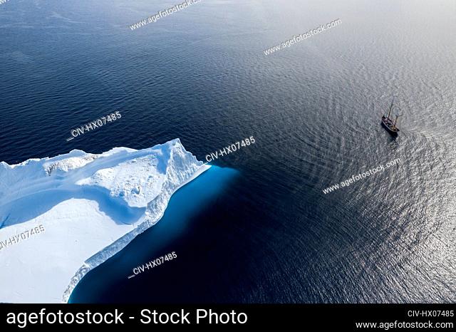 Ship sailing past arctic iceberg on sunny Atlantic Ocean Greenland