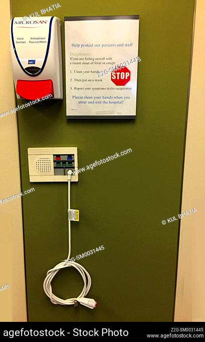 Safety instructions and an emergency apparatus with a cord in a hospital clinic, Ontario, Canada. Disinfectant. Two languages. English, French