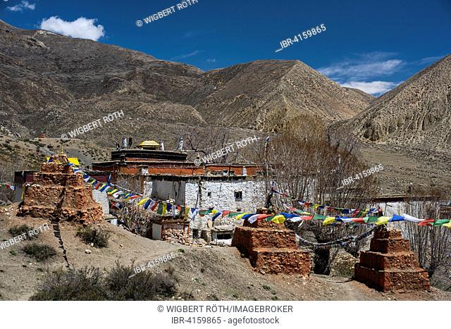Ghar Gompa of Lo Gekar with prayer flags in front of mountain landscape, probably the oldest Buddhist monastery in Nepal, from the 8th century