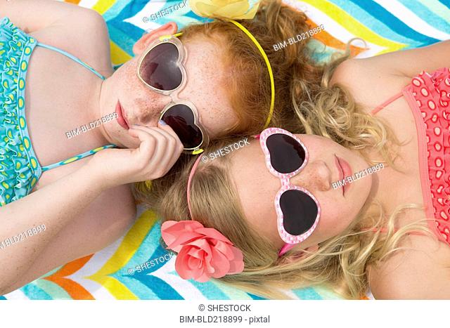 Caucasian girls sunbathing in heart-shaped sunglasses