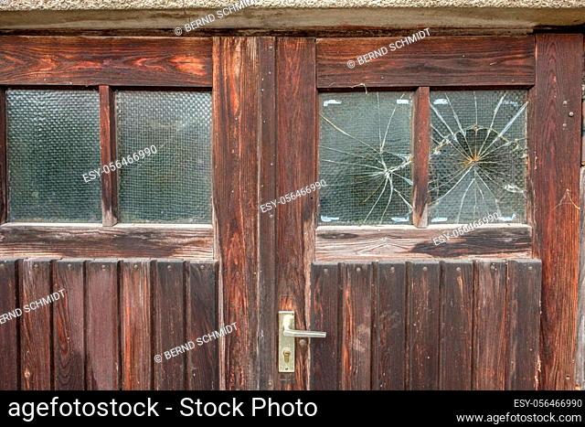 Wooden door with broken window glass close-up