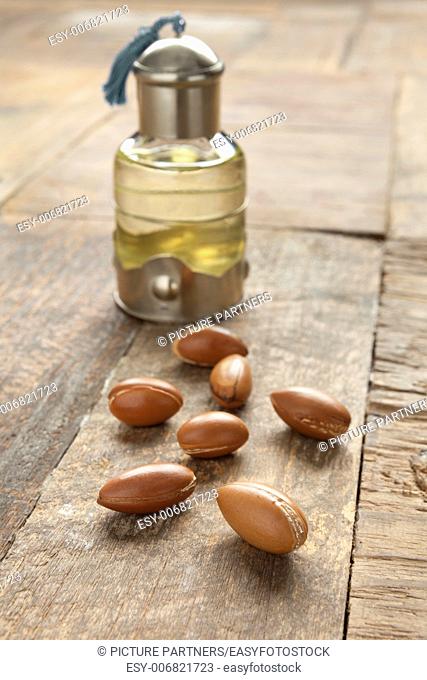 Bottle of argan oil and nuts on the table