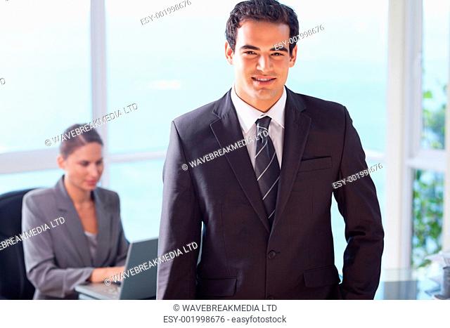 Smiling young businessman with colleague behind him