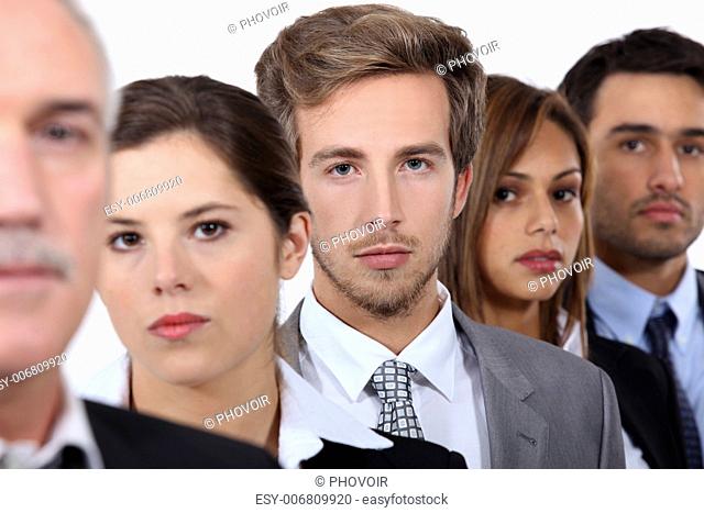 Closeup of the faces of a group of serious young executives and their older boss