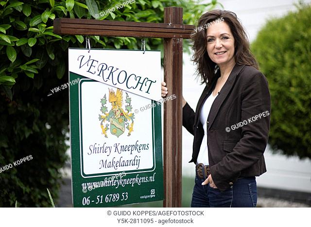 Tilburg, Netherlands. Portrait of a female real estate agent, in front of a residential house just being sold